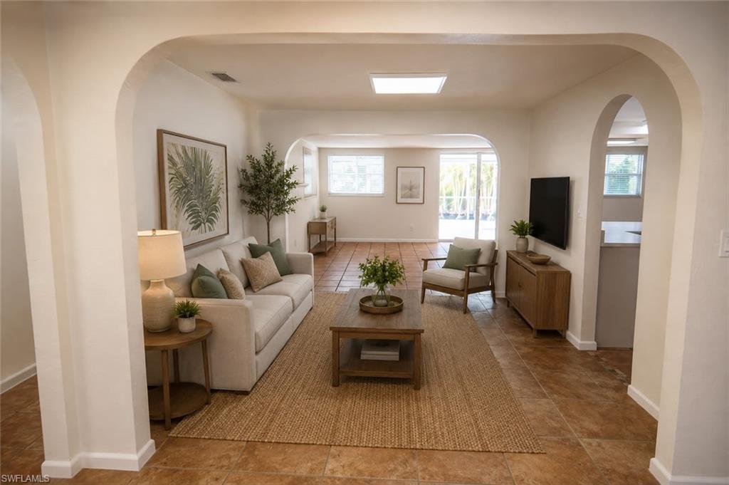 Image 4: Spacious living area featuring arched doorways, light-toned wall finishes, and expansive tile flooring