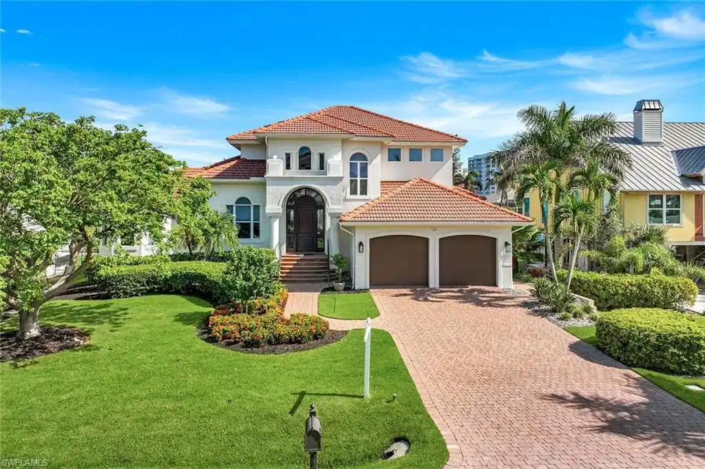 Image 1: Mediterranean / spanish home featuring decorative driveway, stucco siding, a garage, a front lawn, and a tiled roof