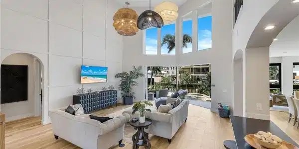 Image 2: Living room featuring arched walkways, light wood-style flooring, recessed lighting, and a towering ceiling