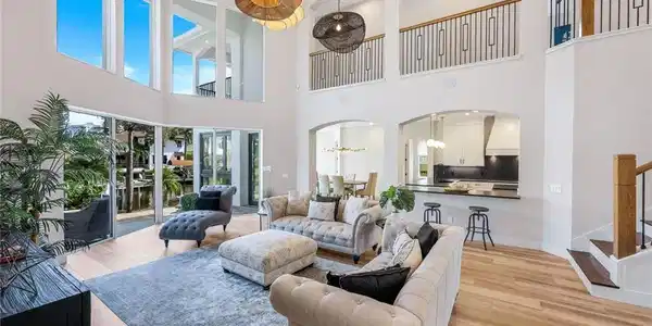 Image 3: Living area featuring a chandelier, arched walkways, stairway, light wood-type flooring, and a towering ceiling