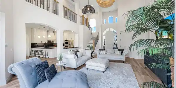 Image 4: Living room featuring wood finished floors, a chandelier, stairs, a towering ceiling, and recessed lighting