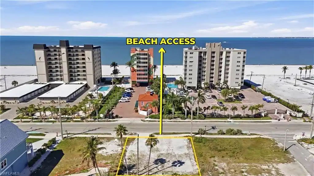 Image 1: Vacant land parcel featuring mature palm trees and direct beach access across the street