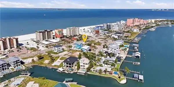 Image 4: Coastal property featuring beach proximity, waterfront access with boat docks, and surrounding residential structures - Virtually Edited Image