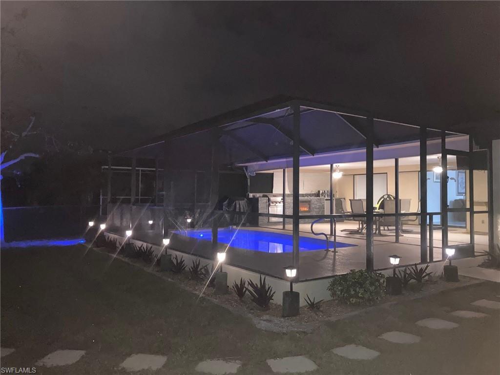 Image 4: Pool at night featuring an outdoor pool, a sunroom, and glass enclosure
