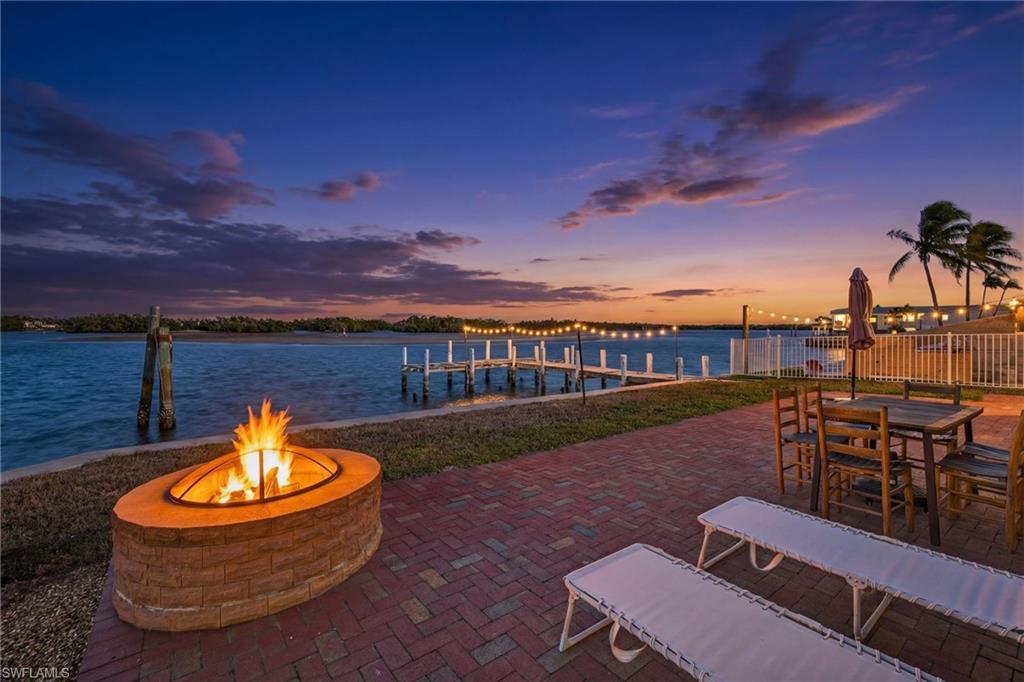Image 1: View of patio / terrace with a dock, a fire pit, a water view, and outdoor dining area