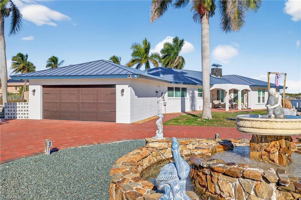 Image 4: View of front of property featuring a standing seam roof, an attached garage, a metal roof, a chimney, and driveway