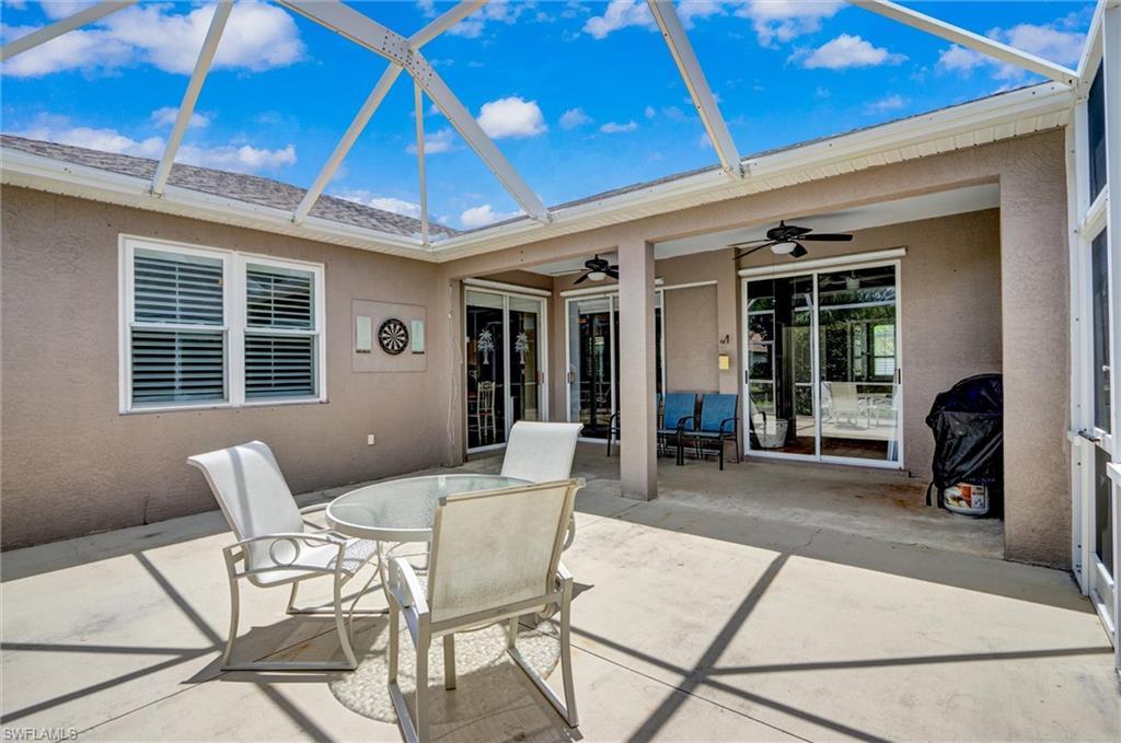 Image 4: Screened-in patio featuring a concrete slab, multiple sliding glass doors, and two exterior ceiling fans
