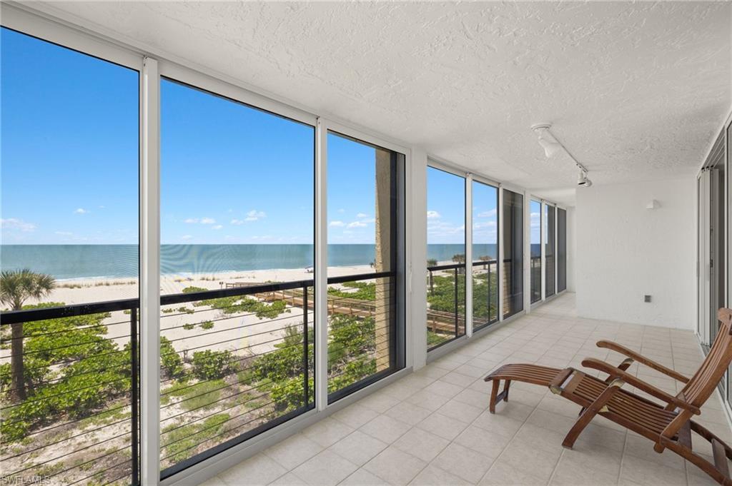 Image 3: Sunroom with floor to ceiling windows, view of water and beach, rail lighting, a textured ceiling, and tile patterned floors