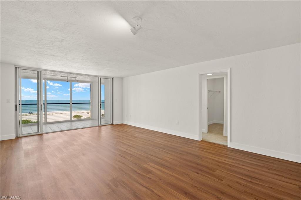 Image 4: Empty room featuring a water view, floor to ceiling windows, wood finished floors, and a textured ceiling