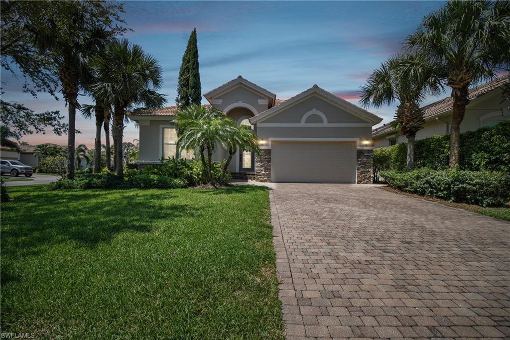 Image 1: Contemporary stucco exterior with a stone accent facade, a paver driveway, an attached garage, and mature palm trees