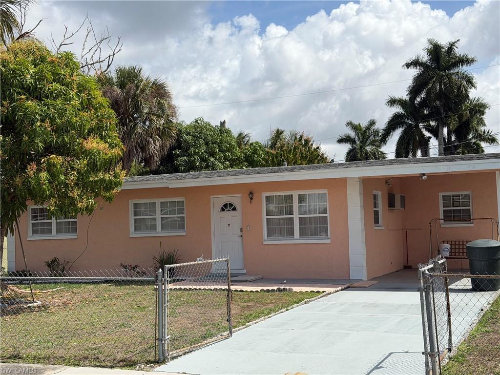 Image 2: View of front of home featuring a gate, a carport, a fenced front yard, stucco siding, and concrete driveway