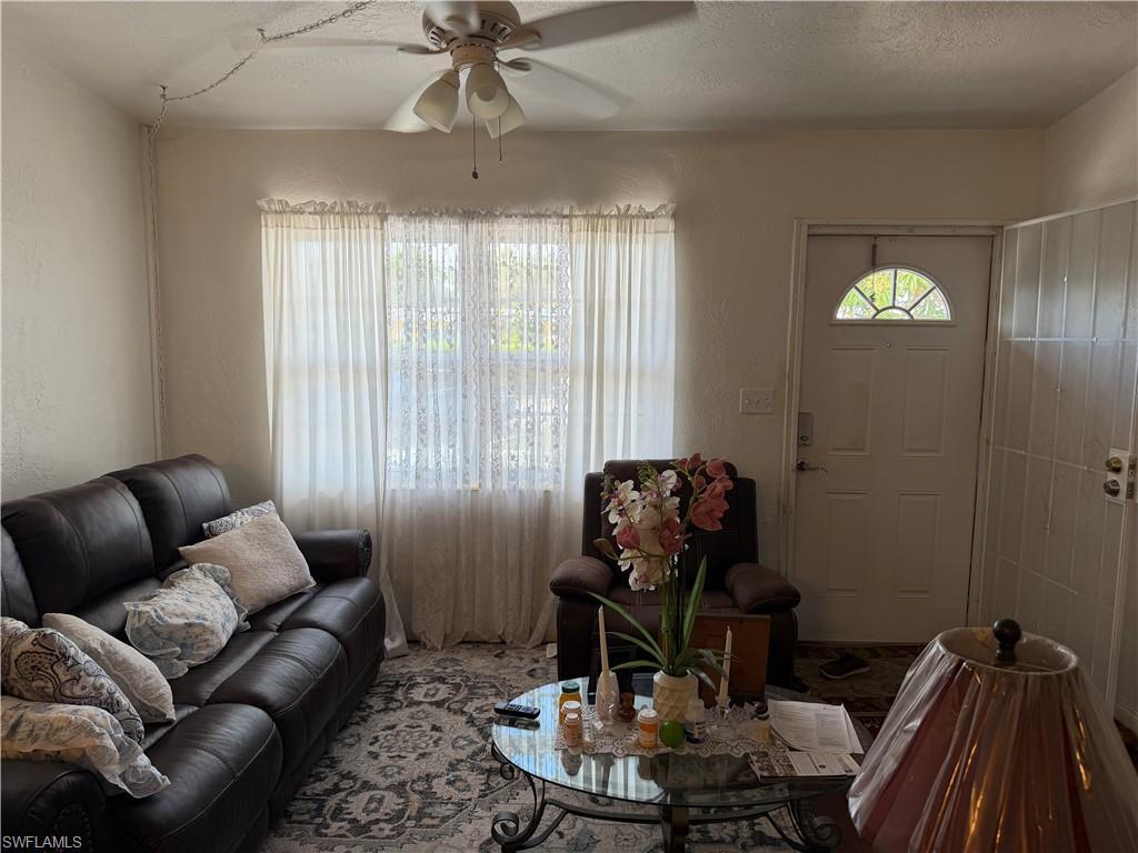 Image 3: Living area with ceiling fan, a textured ceiling, and a textured wall