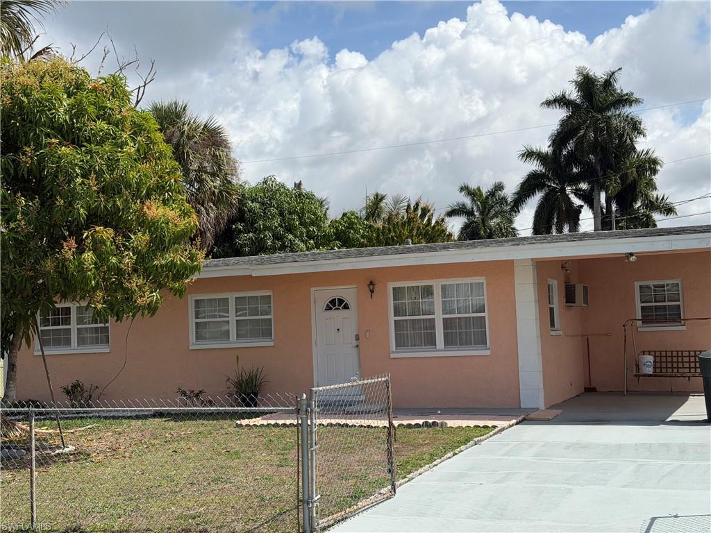 Image 4: Ranch-style home with an attached carport, a gate, stucco siding, and driveway