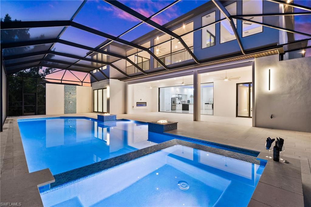 Image 3: Pool at dusk with an in ground hot tub, a lanai, ceiling fan, and a patio