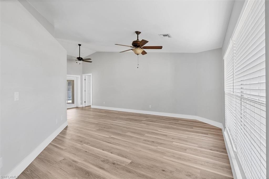 Image 2: Empty room with light wood-style floors, vaulted ceiling, plenty of natural light, and a ceiling fan