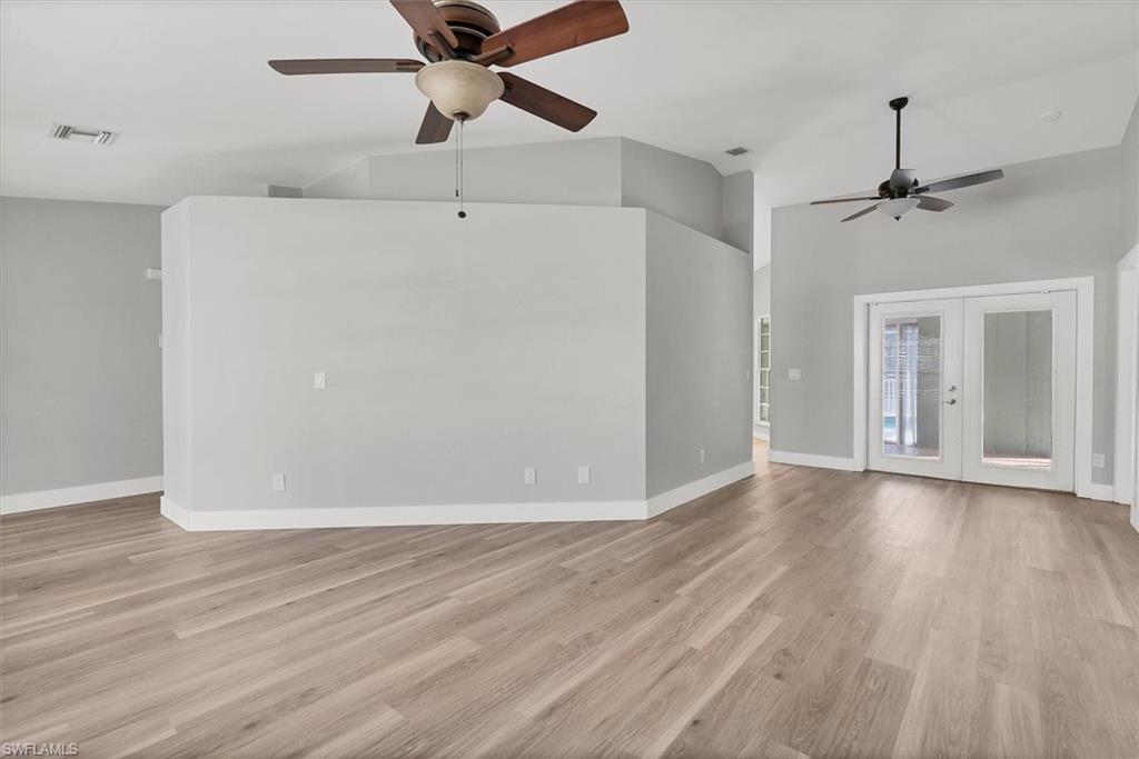 Image 3: Unfurnished living room with french doors, light wood-style floors, ceiling fan, and high vaulted ceiling