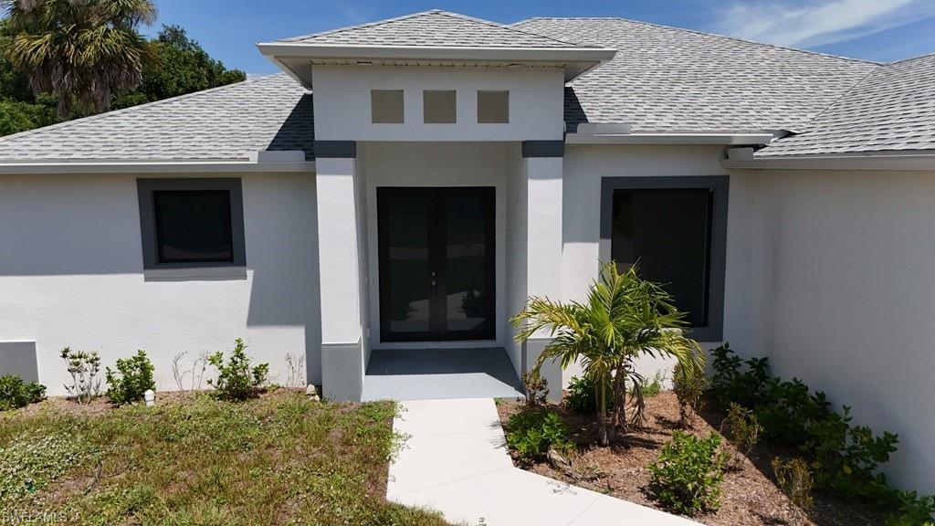 Image 1: Contemporary stucco exterior featuring a dual-door entryway, architectural window framing, and a light gray shingle roof