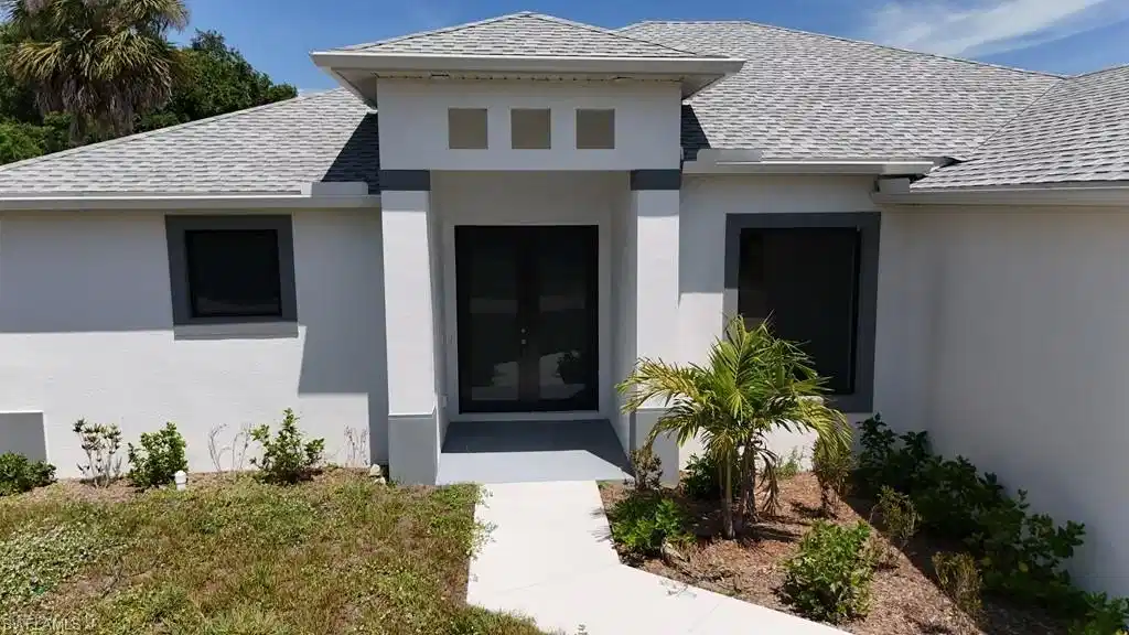 Image 1: Contemporary stucco exterior featuring a dual-door entryway, architectural window framing, and a light gray shingle roof