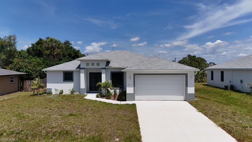 Image 2: Contemporary single-story residence featuring a two-car garage, concrete driveway, and a light gray shingle roof