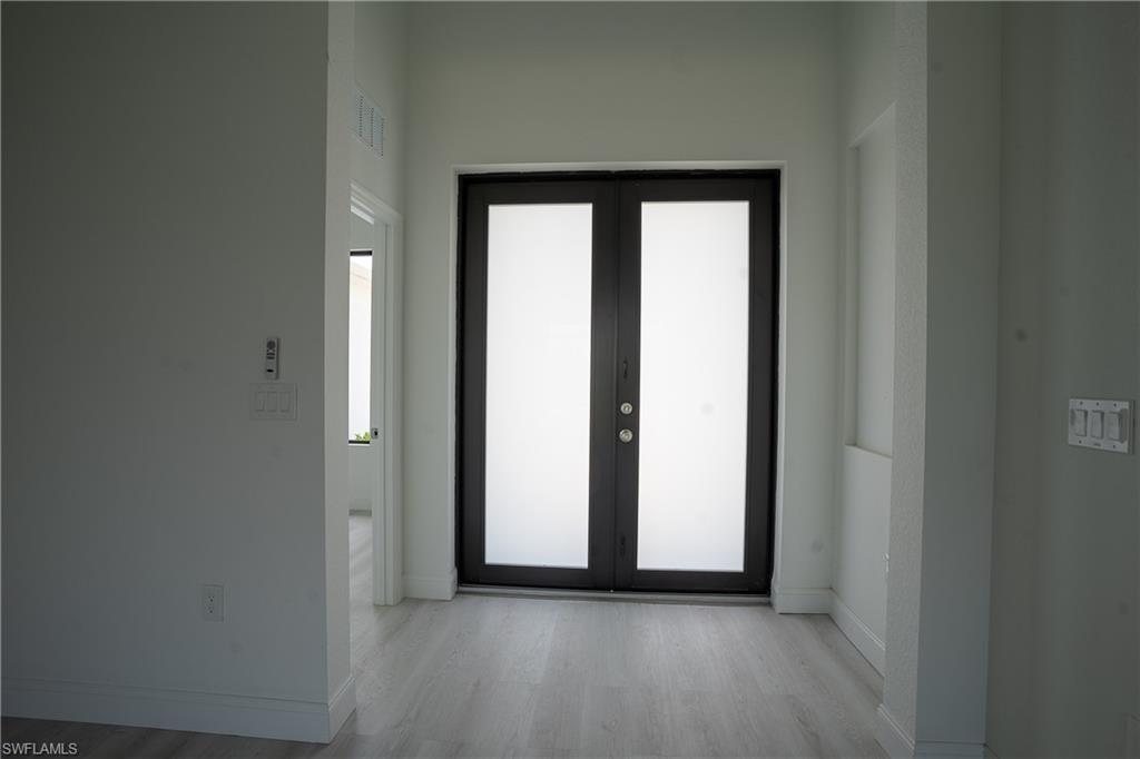 Image 4: Double entry doors featuring frosted glass panels and dark frames, complemented by light wood-finish flooring