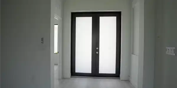 Image 4: Double entry doors featuring frosted glass panels and dark frames, complemented by light wood-finish flooring