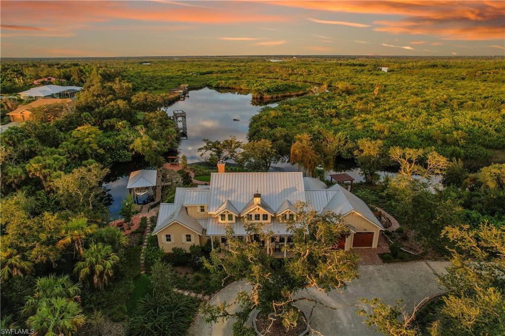 Image 1: Aerial view showcasing the residence nestled amid lush preserve with Deep Creek winding just beyond, offering exceptional privacy and serene natural surroundings