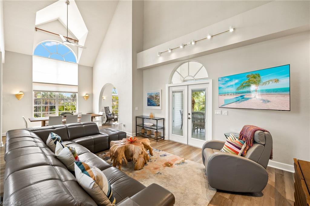 Image 4: Living room featuring high vaulted ceiling, french doors, plenty of natural light, arched walkways, and wood finished floors