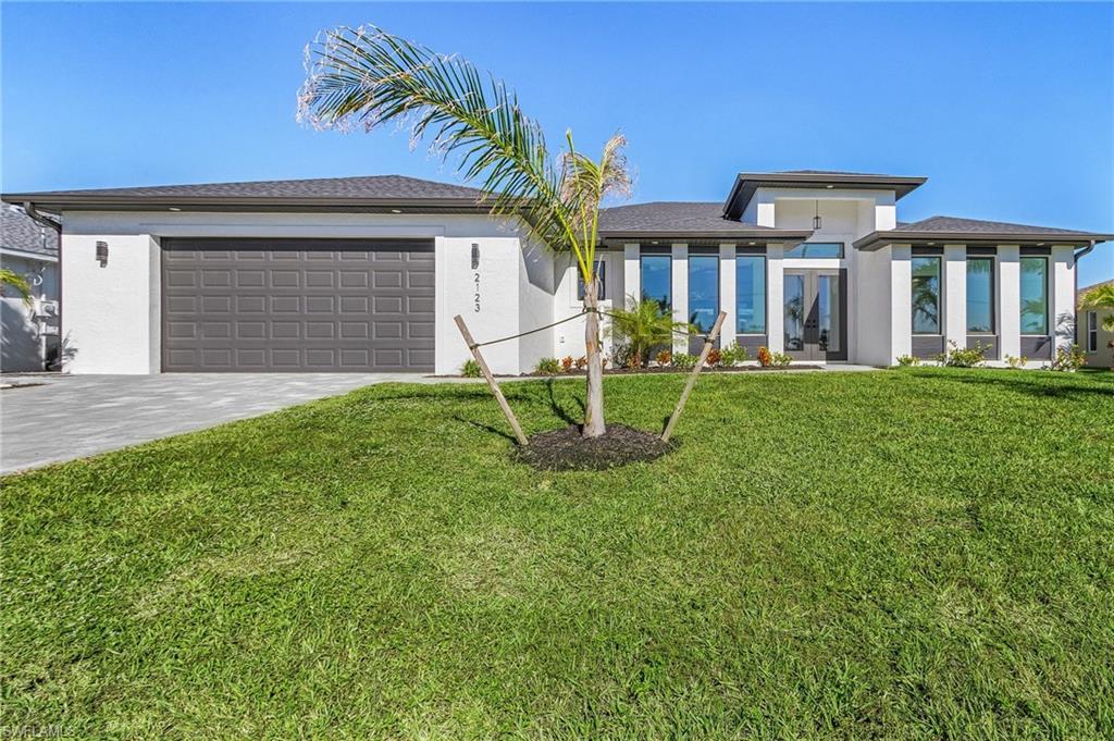 Image 3: View of front of property with a garage and a front lawn