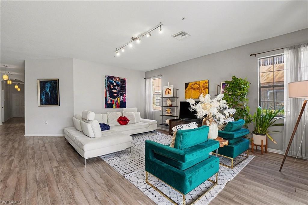 Image 1: Living area featuring light wood finished floors and rail lighting