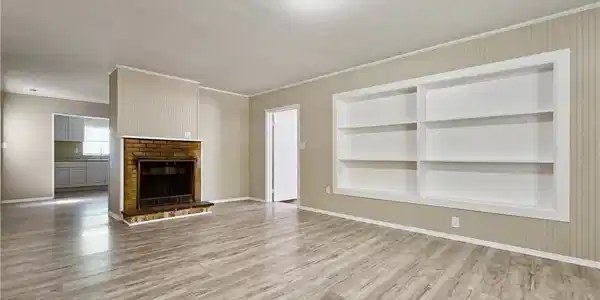 Image 2: Unfurnished living room featuring a brick fireplace, built in features, and hardwood / wood-style flooring