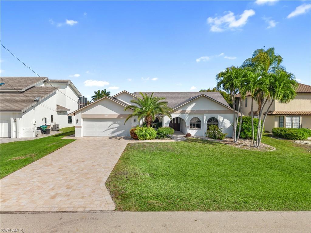 Image 2: View of front of house featuring a front yard, driveway, an attached garage, and stucco siding