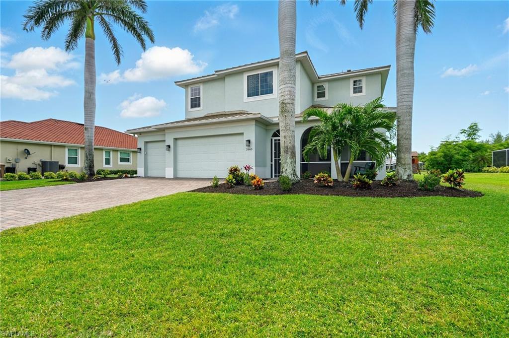 Image 3: Traditional-style home featuring stucco siding, decorative driveway, a garage, central AC, and a front lawn