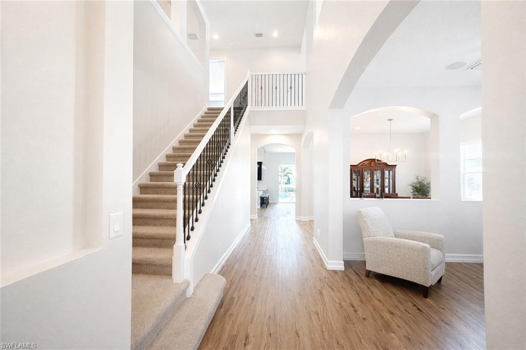 Image 4: Foyer featuring arched walkways, wood finished floors, a high ceiling, and hanging lights