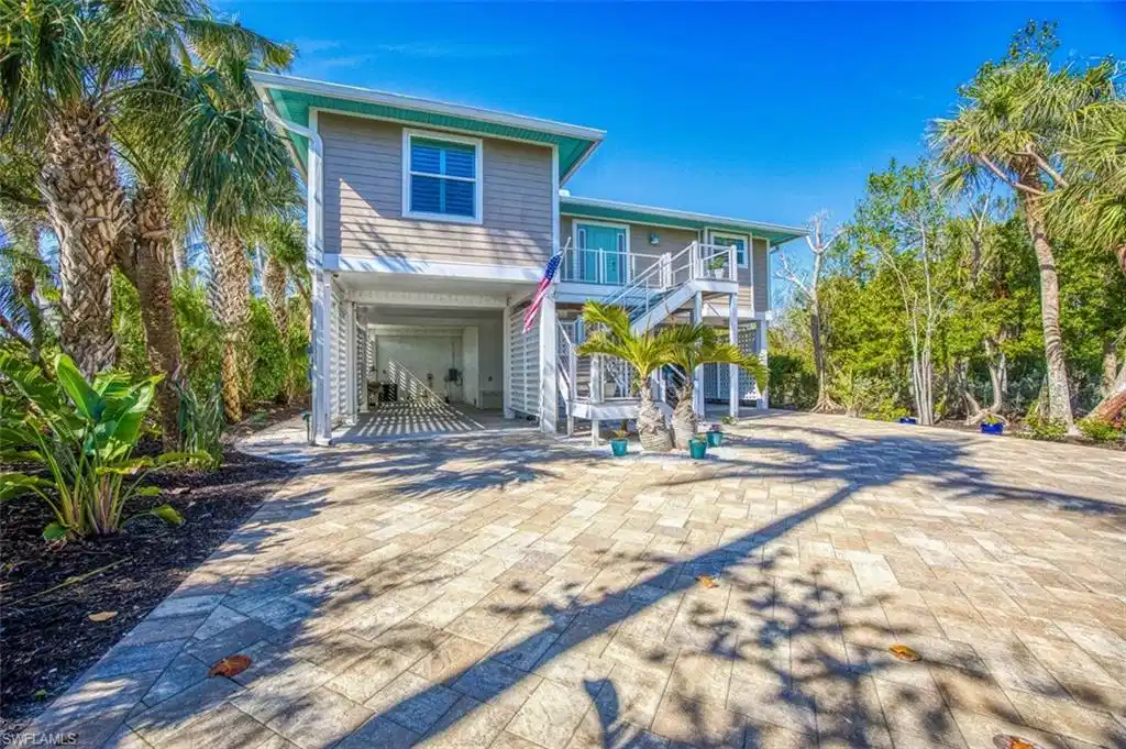 Image 1: Coastal inspired home with a carport, stairway, decorative driveway, a deck, and a patio