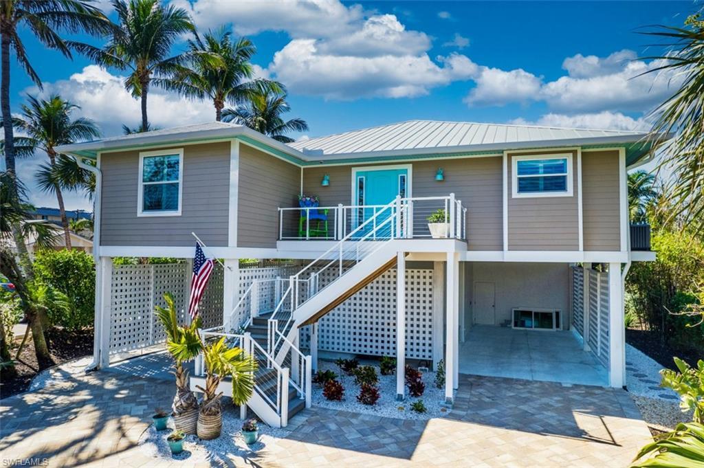 Image 4: View of front of home featuring a carport, a patio, stairs, and a wooden deck