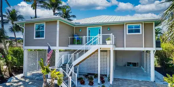 Image 4: View of front of home featuring a carport, a patio, stairs, and a wooden deck
