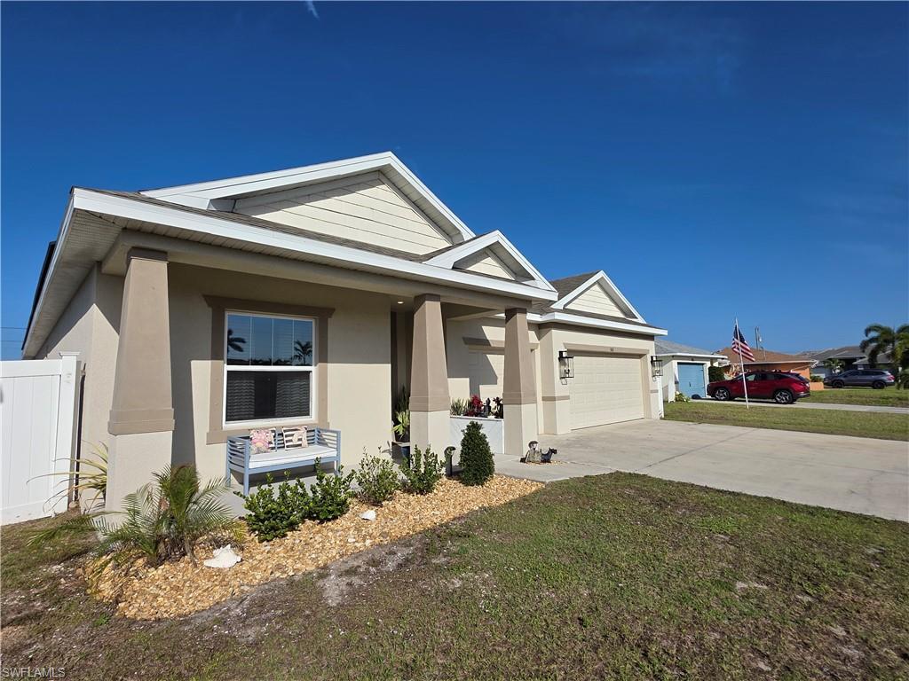 Image 2: View of front of property featuring stucco siding, a porch, a garage, concrete driveway, and a front yard