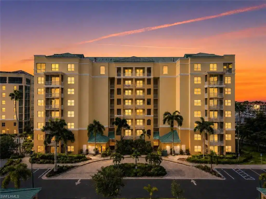 Image 1: Multi-story building with a light-toned stucco exterior and a green tile roof