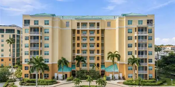Image 2: Multi-story residential building with a pastel yellow exterior, featuring multiple private balconies and screened lanais