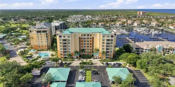 Image 4: Multi-story residential complex with covered parking, an outdoor pool, and a marina with boat slips