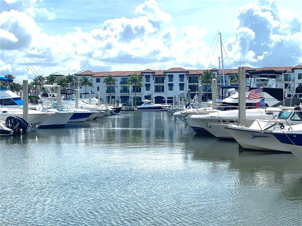 Image 1: Waterfront property featuring a private marina with multiple boat slips, white stucco exterior, and red tile roofing