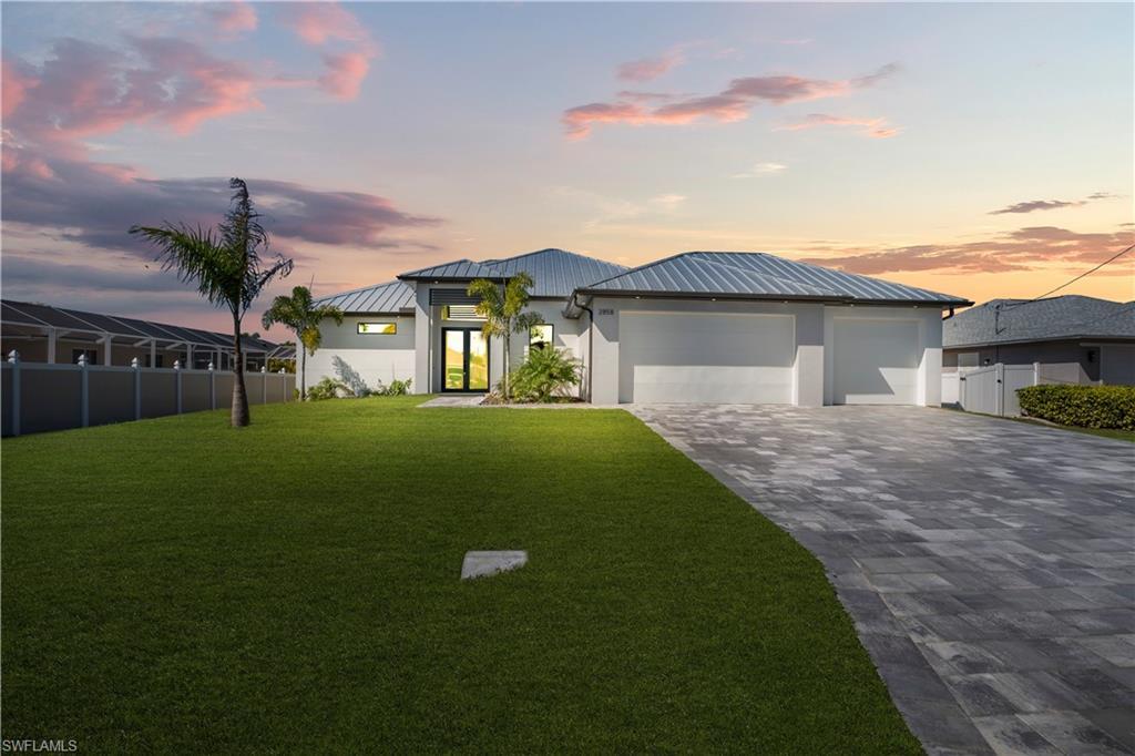Image 1: View of front of house with a standing seam roof, an attached garage, decorative driveway, stucco siding, and french doors