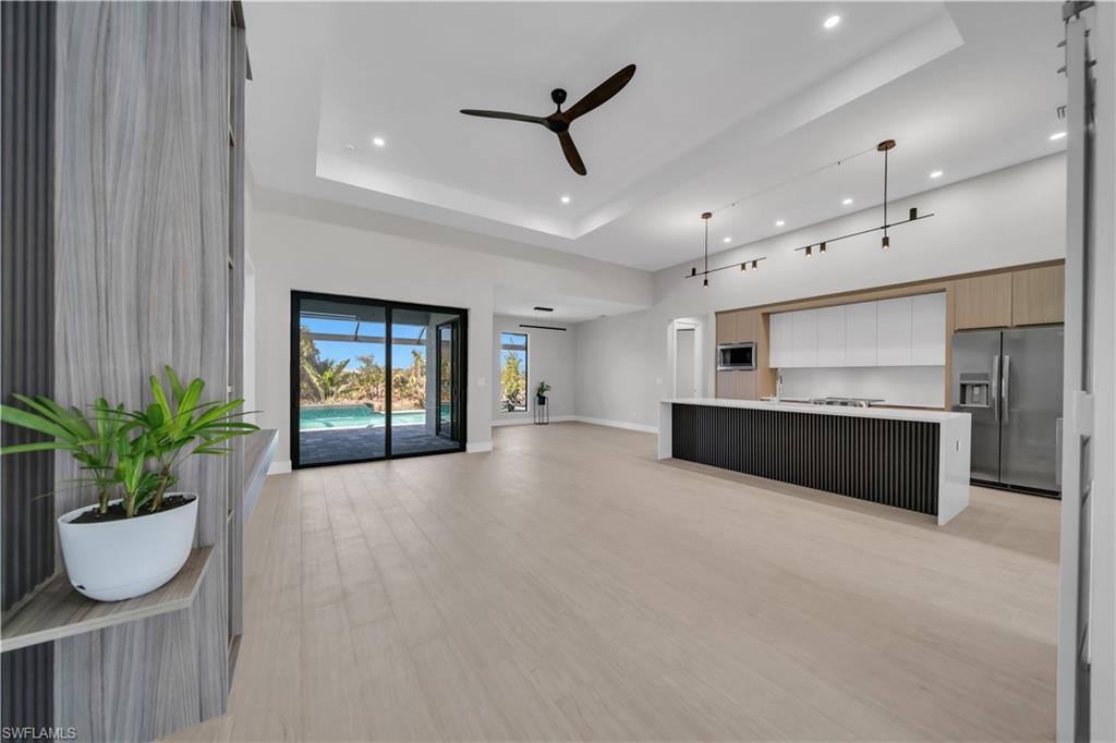 Image 2: Unfurnished living room featuring ceiling fan, a raised ceiling, light wood-style flooring, and recessed lighting