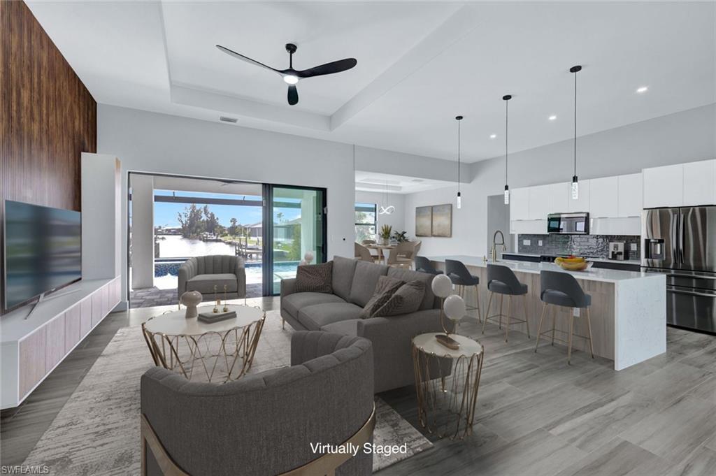Image 2: Living room featuring a ceiling fan, light wood-style flooring, recessed lighting, a tray ceiling, and a towering ceiling