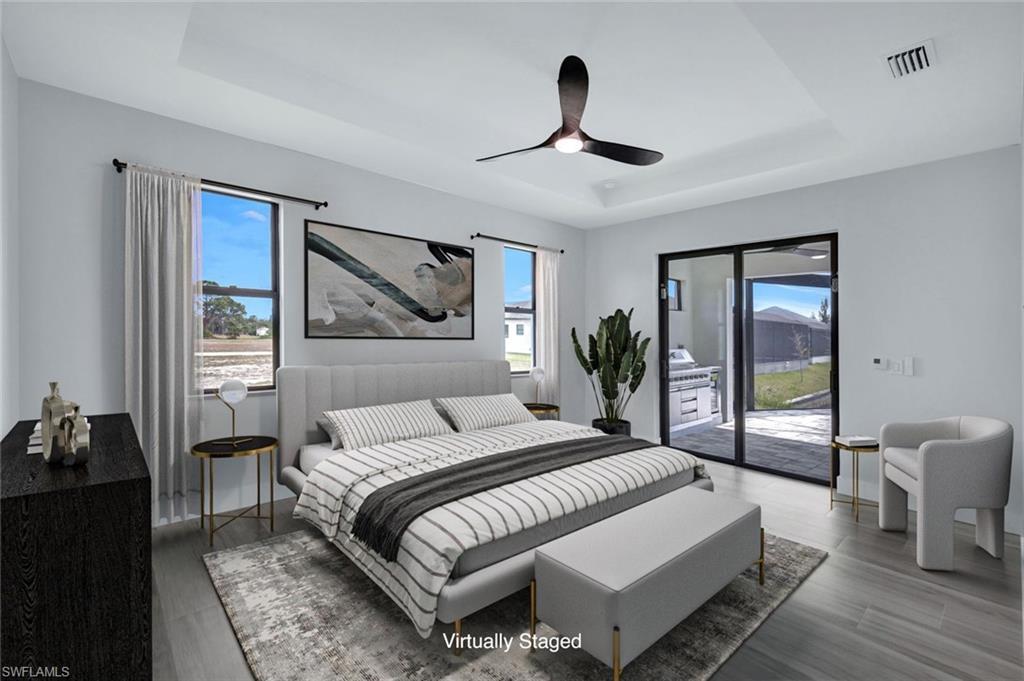 Image 3: Bedroom with a tray ceiling, visible vents, wood finished floors, and access to exterior