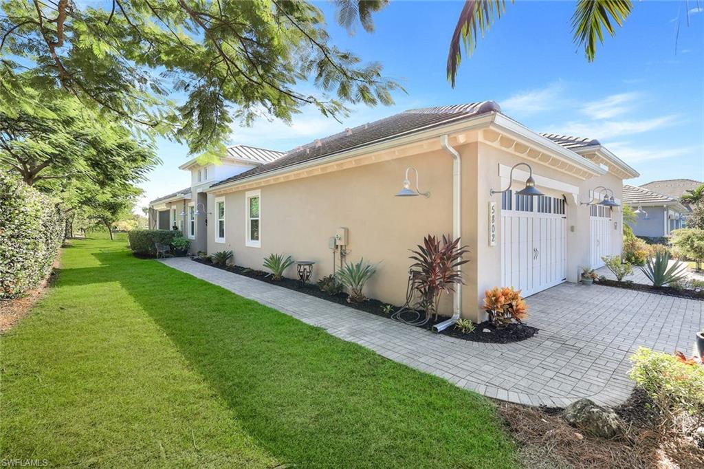 Image 3: View of side of home with a yard, an attached garage, stucco siding, and decorative driveway