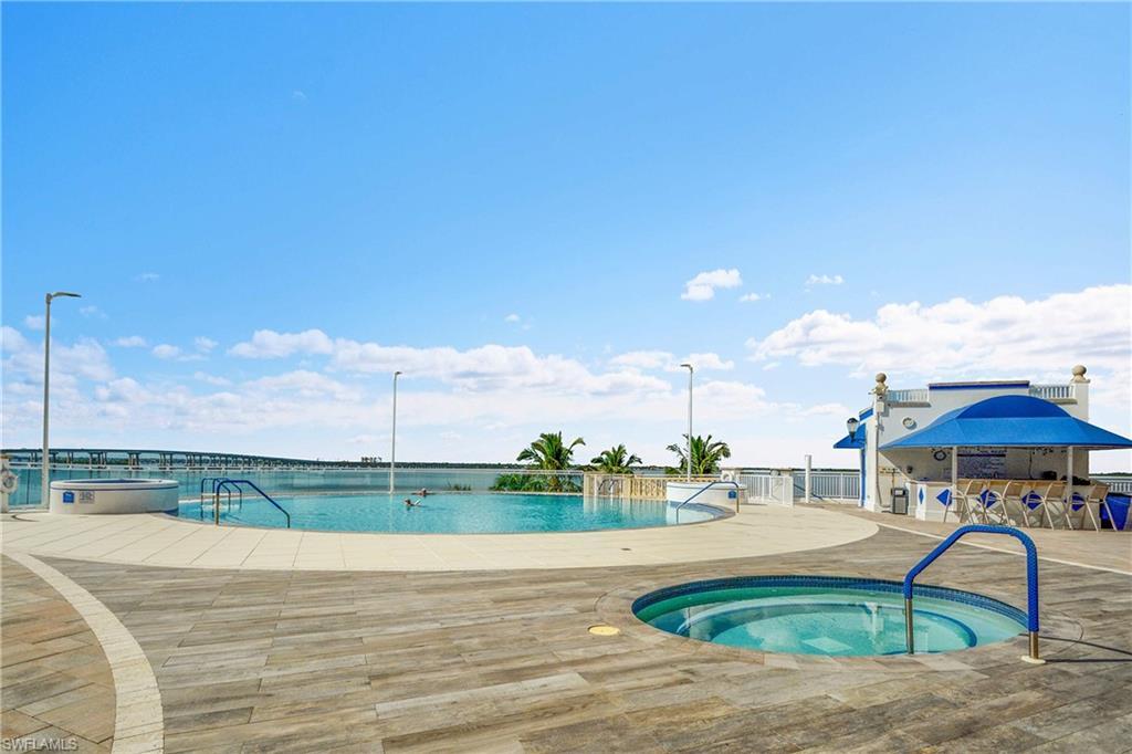 Image 4: Community pool with a hot tub and a patio area
