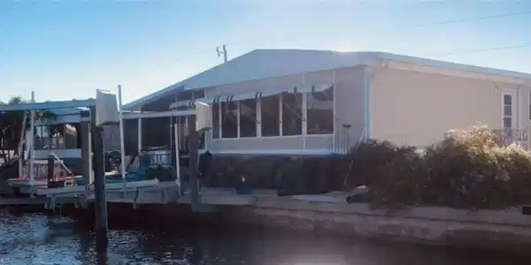 Image 2: Rear view of house featuring a water view, boat lift, and a sunroom