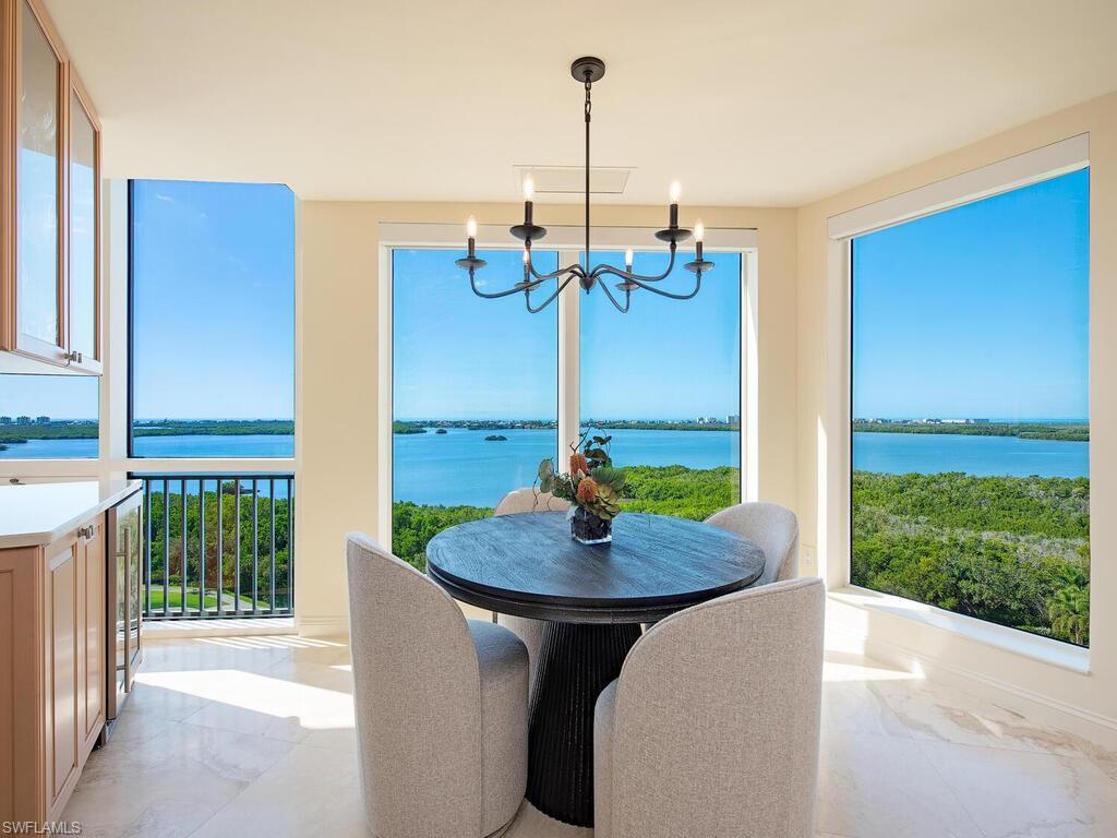 Image 2: Great room dining with bar, featuring marble tiled flooring, a water view, healthy amount of natural light, and a chandelier