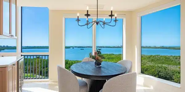 Image 2: Great room dining with bar, featuring marble tiled flooring, a water view, healthy amount of natural light, and a chandelier